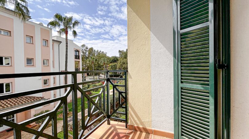 Sunny balcony with green shutters and view of well-maintained garden in Santa Ponça