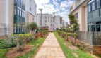 Well-maintained garden path between modern residential buildings in Santa Ponça with Mediterranean palm trees and ornamental shrubs.