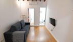 Sala de estar luminosa con sofá gris, suelo de madera, aire acondicionado y vigas de madera en Inca