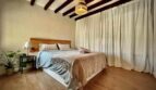 Gemütliches Schlafzimmer mit Holzbalkendecke, Doppelbett und Parkettboden in Inca
