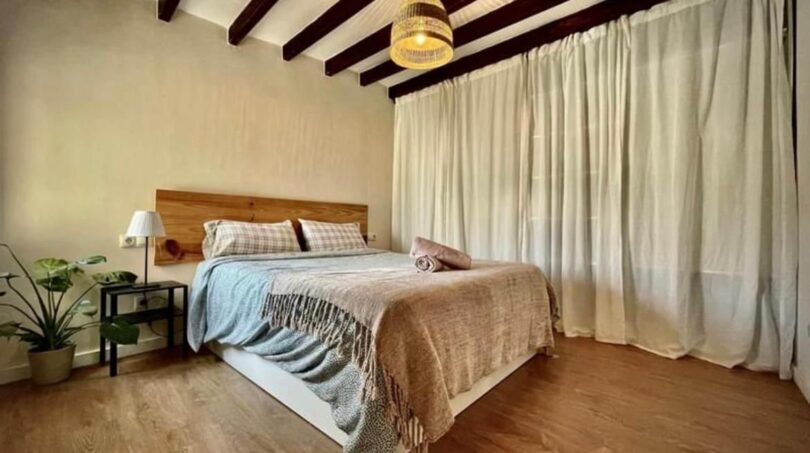 Gemütliches Schlafzimmer mit Holzbalkendecke, Doppelbett und Parkettboden in Inca