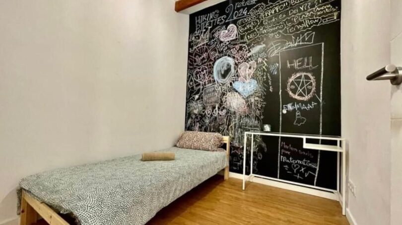 Schlafzimmer mit Einzelbett, Holzboden und kreativ gestalteter schwarzer Kreidetafel-Wand in Inca.