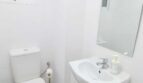 Modernes weißes Badezimmer mit WC, Waschtisch, Spiegel und blauem Handtuch in Inca