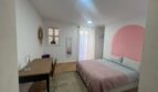 Helles Schlafzimmer mit rosa Akzentwand, Doppelbett, Schreibtisch und Parkettboden in Inca