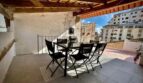 Überdachte Dachterrasse mit schwarzen Gartenmöbeln, Holzbalken und Stadtblick in Inca.