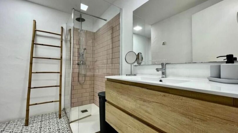 Modernes Badezimmer mit Glasdusche, Holzwaschtisch und Mosaikbodenfliesen in Inca