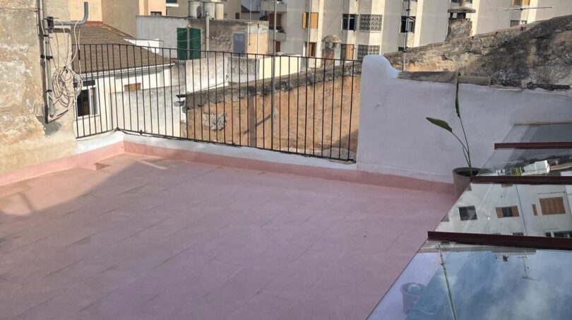 Dachterrasse mit rosa Bodenbelag und Metallgeländer, Blick auf Stadtgebäude in Inca, Mallorca