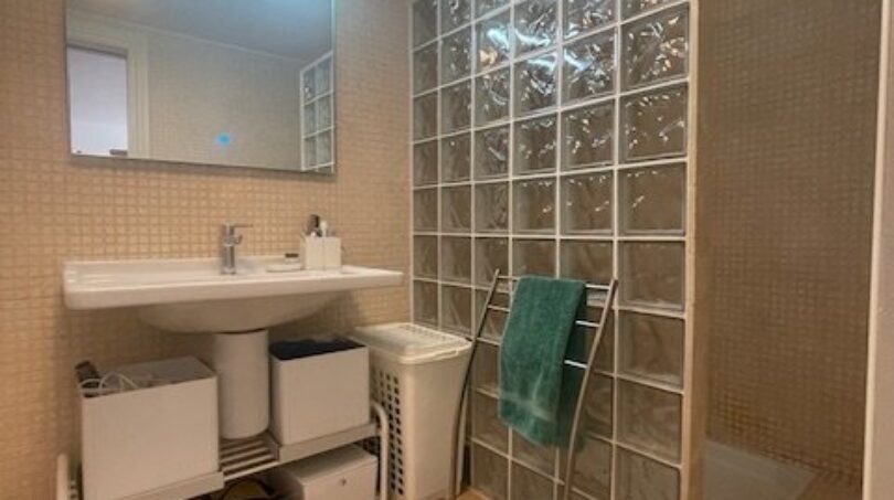 Helles Badezimmer mit Glasbausteinwand, Dusche, Waschtisch und Spiegel im Penthouse Palma de Mallorca.