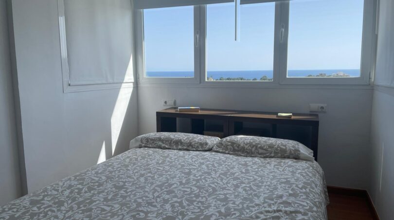 Helles Schlafzimmer des Penthouse in Palma mit Doppelbett und atemberaubendem Meerblick durch große Fenster.