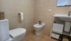 Helles Badezimmer mit WC, Bidet und Waschtisch, cremefarbenen Mosaikfliesen und moderner Beleuchtung im Penthouse Palma.