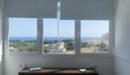 Helles Schlafzimmer im Penthouse mit Doppelbett, Holzkopfteil und Panoramafenster mit Meerblick über Palma de Mallorca.