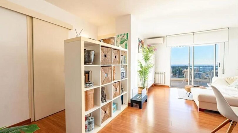 Helles Penthouse-Wohnzimmer mit Regalraumteiler, Holzboden und großer Glasfront mit Meerblick in Palma
