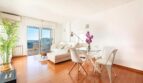 Helles Wohnzimmer mit Holzboden, weißem Sofa, Glasertisc und Balkon mit Meerblick im Penthouse Palma