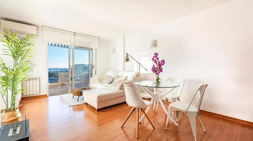 Helles Wohnzimmer mit Holzboden, weißem Sofa, Glasertisc und Balkon mit Meerblick im Penthouse Palma