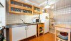 Helle Küche mit Holzschränken, Edelstahlarbeitsplatte, Kühlschrank und Mikrowelle im Penthouse Palma de Mallorca