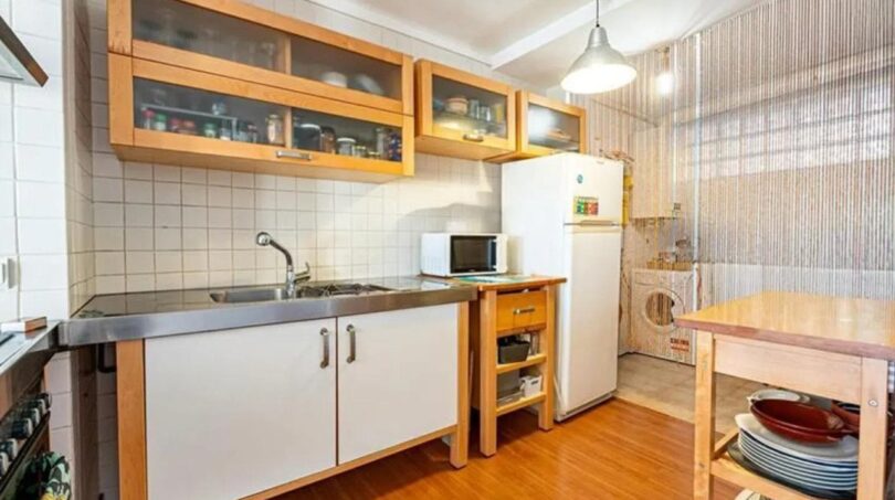 Helle Küche mit Holzschränken, Edelstahlarbeitsplatte, Kühlschrank und Mikrowelle im Penthouse Palma de Mallorca