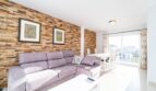 Helles Wohnzimmer mit Steinwand, Sofa und Essbereich, Wohnung in Artà