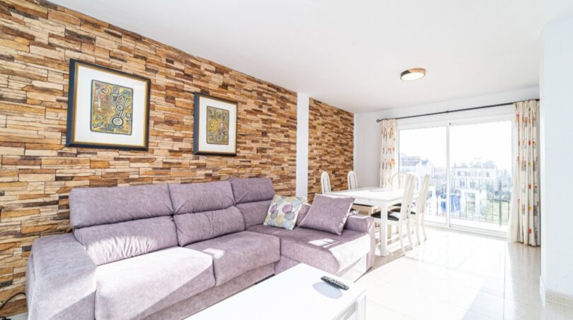 Helles Wohnzimmer mit Steinwand, Sofa und Essbereich, Wohnung in Artà