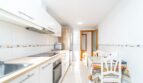 Moderne weiße Küche mit Esstisch, Einbaugeräten und Dekorfliesen in einer Wohnung in Artà.