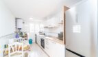 Helle Küche mit weißen Schränken, Holzarbeitsplatte, Einbaugeräten und Essbereich in Wohnung in Artà.