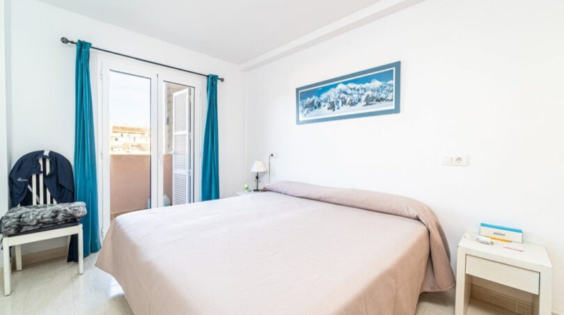 Helles Schlafzimmer mit Doppelbett, Balkon und blauen Vorhängen in exklusiver Wohnung in Artà