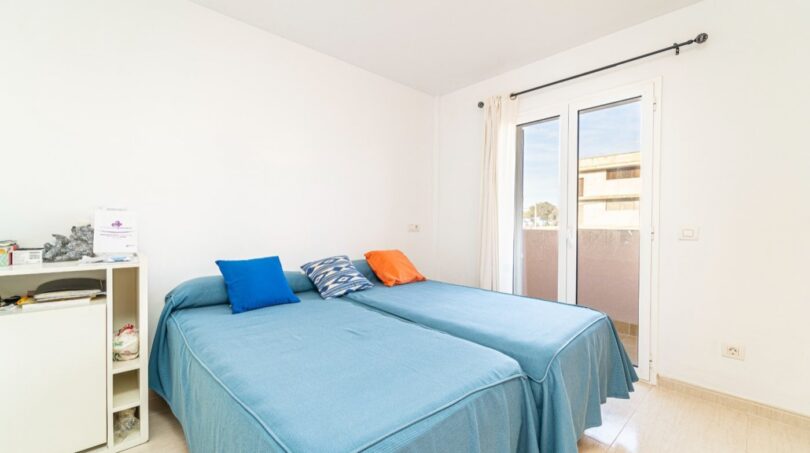 Helles Schlafzimmer mit zwei Einzelbetten, blauen Tagesdecken und Balkonzugang in Wohnung in Artà.