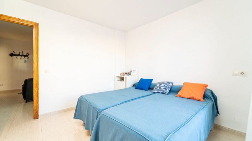 Helles Schlafzimmer mit zwei Einzelbetten, blauen Tagesdecken und bunten Kissen in Wohnung in Artà.