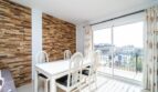 Helles Esszimmer mit weißem Tisch, Steinwandverkleidung und Balkon mit Stadtblick in Artà.