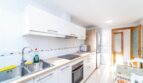 Moderne weiße Küche mit Einbaugeräten, Holzarbeitsplatte und Esstisch in Wohnung in Artà.