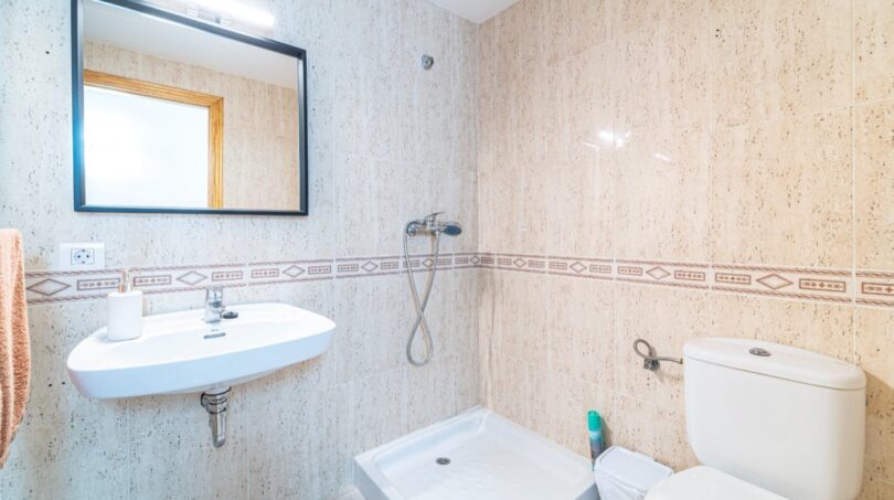 Helles Badezimmer mit Dusche, WC und Waschbecken, beige Fliesenwände mit Zierborte in Wohnung in Artà.