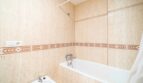 Badezimmer mit Badewanne, Dusche und Bidet, beige Fliesenwände mit dekorativem Bordürenmuster in Artà