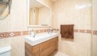 Helles Badezimmer mit Beigefliesen, Holzunterschrank, großem Spiegel und Dusche in exklusiver Wohnung in Artà.