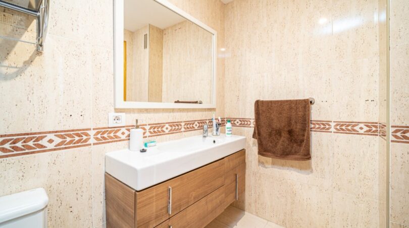 Helles Badezimmer mit Beigefliesen, Holzunterschrank, großem Spiegel und Dusche in exklusiver Wohnung in Artà.