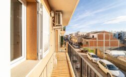 Sunny balcony of the apartment in Artà with metal railing, air conditioning and view of the quiet city street.