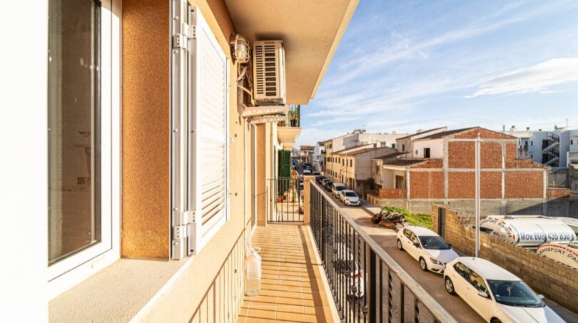 Sunny balcony of the apartment in Artà with metal railing, air conditioning and view of the quiet city street.