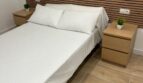 Helles Schlafzimmer mit Doppelbett, Holz-Lattenrückwand und zwei Nachttischen in kernsanierter Wohnung Palma