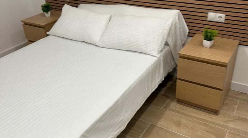 Helles Schlafzimmer mit Doppelbett, Holz-Lattenrückwand und zwei Nachttischen in kernsanierter Wohnung Palma