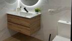 Modernes Badezimmer mit rundem LED-Spiegel, schwebendem Holzwaschtisch und Marmorfliesen in sanierter Wohnung Palma