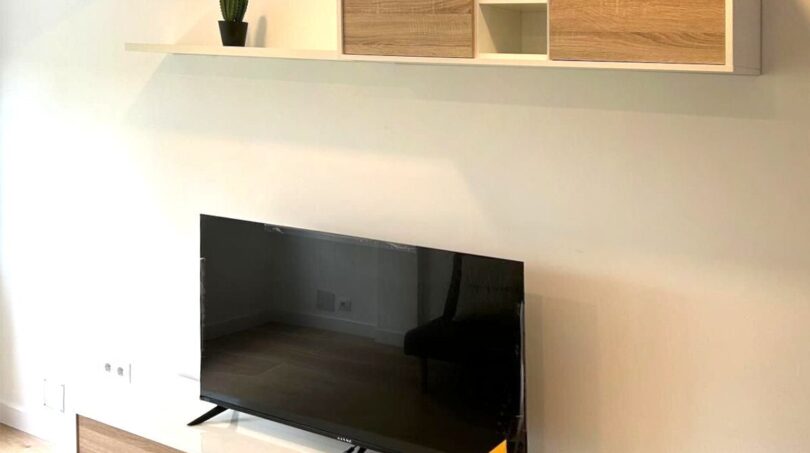 Modernes TV-Möbel mit Holzoptik und Wandregal im Wohnzimmer der sanierten Wohnung in Palma