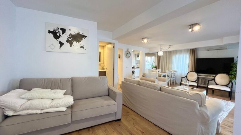 Helles Wohnzimmer mit beigen Sofas, Holzboden und Weltkartenkunst in Strandnähe, El Arenal