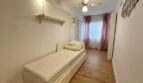 Helles Schlafzimmer mit Einzelbett, Holzboden, Deckenventilator und rosa Vorhängen in Strandnähe, Palma