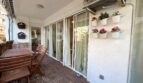 Überdachte Terrasse mit Holzmöbeln, Glasschiebetüren und Wandblumentöpfen in Strandnähe, Palma de Mallorca