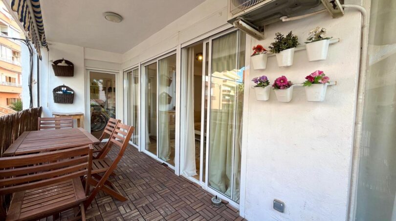 Überdachte Terrasse mit Holzmöbeln, Glasschiebetüren und Wandblumentöpfen in Strandnähe, Palma de Mallorca