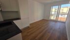  Wohnzimmer mit offner Küche und Zugang zum Balkon
