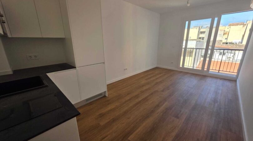  Wohnzimmer mit offner Küche und Zugang zum Balkon
