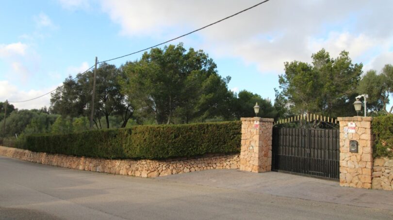 Einfahrt einer Finca in Palma mit schmiedeeisernem Tor, Natursteinmauer und üppiger Bepflanzung
