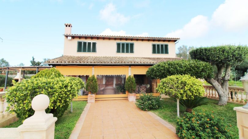 Außenansicht einer gemütlichen Finca in Palma de Mallorca mit gepflegtem Garten, Terrakotta-Weg und mediterraner Vegetation.