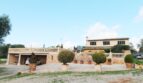 Außenansicht einer mediterranen Finca in Palma de Mallorca mit Steinmauer, Balustrade, Carport und gepflegten Buchsbäumen.