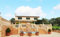 Außenansicht der Finca in S'aranjassa mit Brunnen, Balustrade, Terrasse und mediterranem Garten.