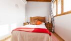 Schlafzimmer der Finca Palma de Mallorca mit Holzbett, roter Tagesdecke, Klimaanlage und Holzdecke